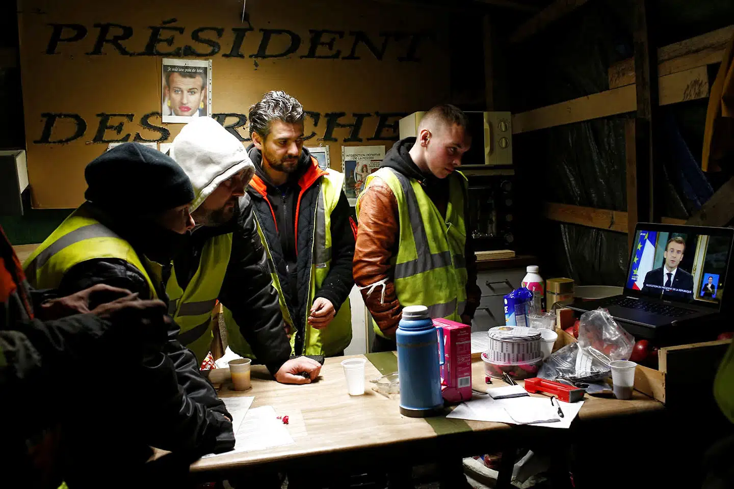 En gruppe fra protestbevægelsen De Gule Veste nær den vestfranske by Bouguenais følger med skeptiske miner præsident Macrons TV-tale.