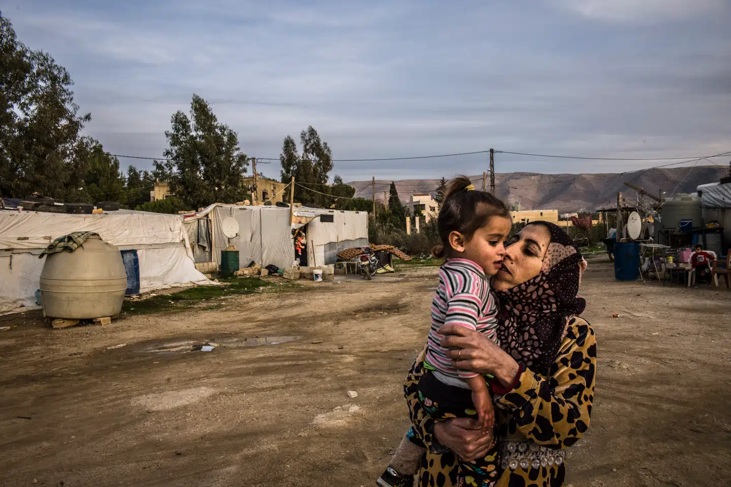 Kvinde fra Daraa kysser barn i improviseret teltlejr. Hun og familien har boet i den ulovlige teltlejr i snart syv år. I Libanon har de intet – men i Syrien endnu mindre.