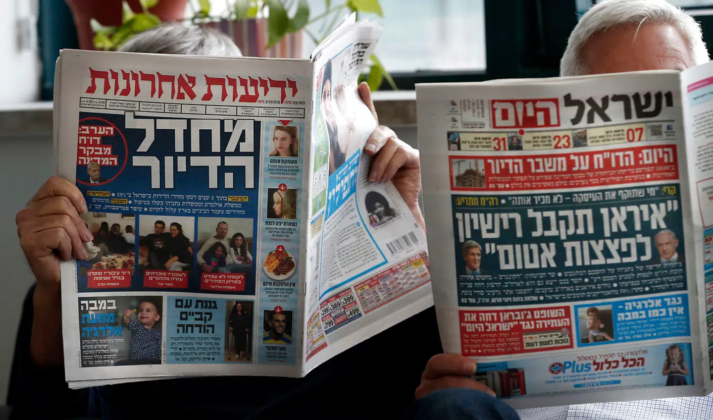 To israelske mænd læser aviser. Til venstre Yediot Ahronot og til højre gratisavisen Israel Hayom.