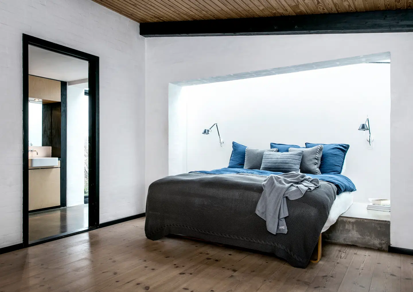 Med en enkelt meters tilbygning fik Camilla Gullits og hendes mand skabt en kæmpe forvandling. Det forhøjede repos under sengen og badeværelsesgulvet er støbt i stenhård epoxy, som får blødt modspil af tekstiler af eget design. Sengelamper fra Artemide.