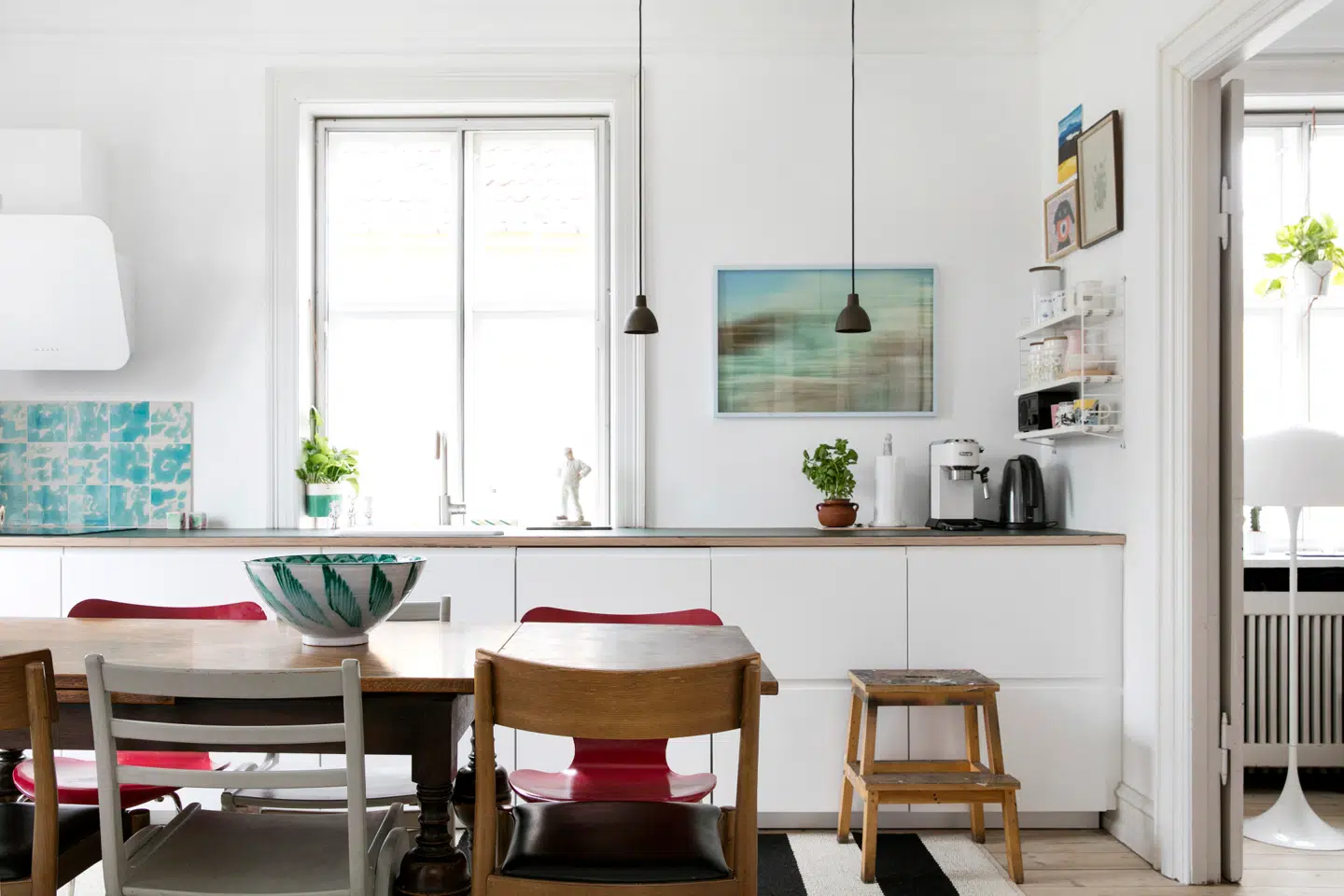 Den største forandring, Wendy Plovmand og hendes mand har lavet ved boligen, er, at de har flyttet køkkenet ind i en af de tre stuer en suite, så alle familiens fællesrum ligger samlet. Køkkenet er fra Ikea, mens parret selv har beklædt en billig bordplade med linoleum. Overalt i hjemmet giver Wendy Plovmands egne værker farve og stil; i køkkenet er fliserne endda lavet af hende selv.