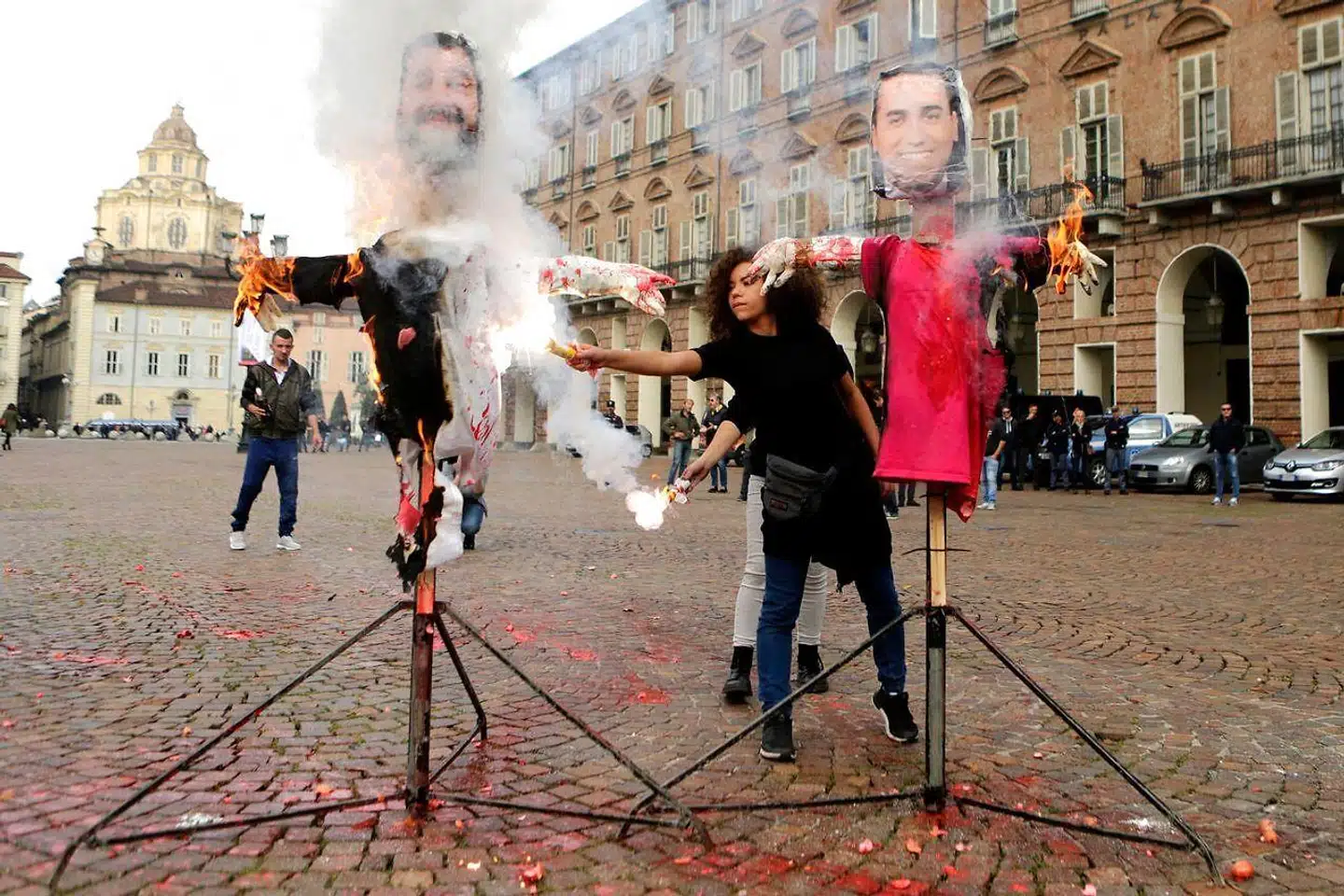 Legas Matteo Salvini og Femstjernebevægelsens Luigi Di Maio taber ansigt over for deres vælgere, hvis de giver efter for pres fra EU for at indføre en ansvarlig økonomisk politik. De to partiledere og ministre risikerer dog at blive straffet af de finansielle markeder, hvis de ikke gør det. Her brændes dukker af dem under en studenterdemonstration mod deres uddannelsespolitik.