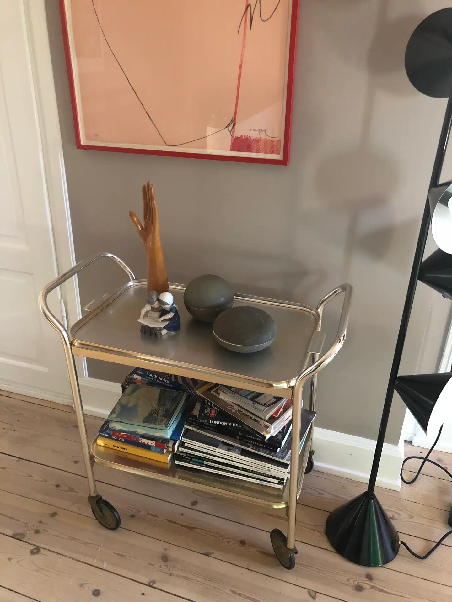 Barvogn og vintage-plakat fra Helle Thygesen Art & Antiques, dekorative loppefund og gulvlampe fra Atelier Areti hos The Apartment.