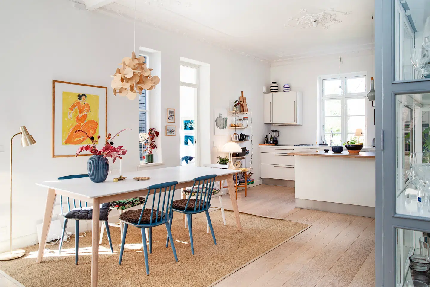 Spisepladsen er placeret midt i det store køkken-alrum, og det giver en mere dynamisk indretning, end hvis bordet var stillet op a en væg. Selve bordet er fra IDEMøbler, mens FDB-stolene er fundet på dba.dk. Det store, gule billede er et litografi af Hans Voigt Steffensen og er ét af Christina J. Jørgensens kæreste ejer; det er et arvestykke fra hendes mor. Over bordet hænger en trælampe fra Normann Copenhagen, og under det ligger et stort gulvtæppe fra Ikea. Gulvlampen i messing er fra et loppemarked, mens vasen er fra Kähler.