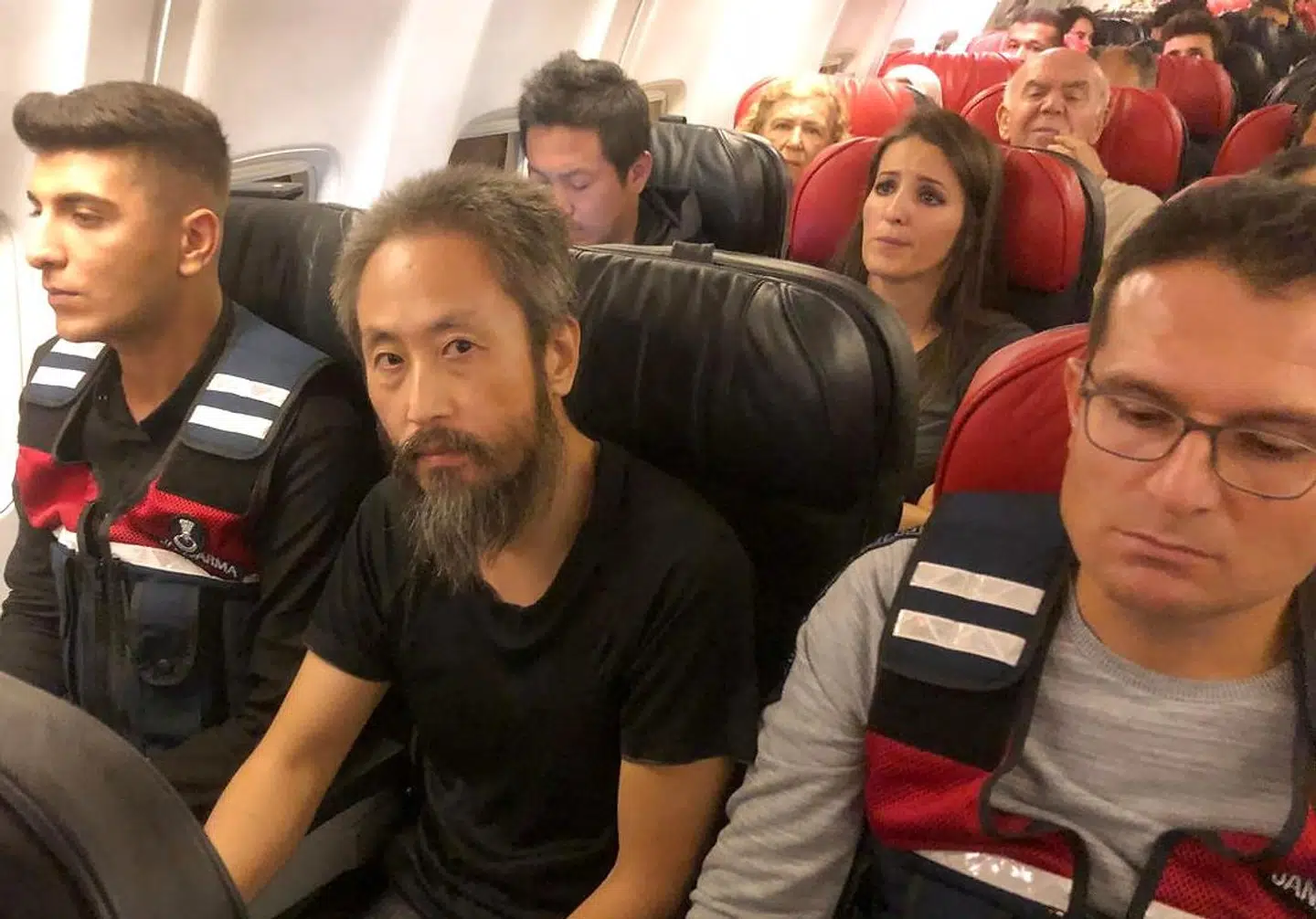Den japanske journalist Jumpei Yasuda på et fly mod Tyrkiet omgivet af tyrkiske betjente efter at have været fanget i 40 måneder i Syrien.