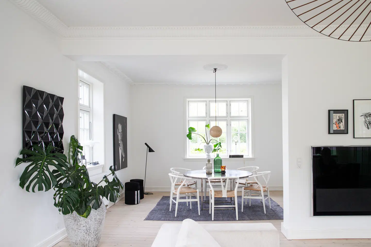 Da familien flyttede ind, havde de først indrettet spisestue der, hvor stuen er i dag. Flowet fungerede dog ikke i hverdagen, og derfor valgte de at bytte rundt på spisestuen og stuen, sådan som det ser ud i dag. Her har Nanna Meyer indrettet med danske designikoner som Y-stolen af Hans J. Wegner fra Carl Hansen & Søn, Arne Jacobsen-gulvlampen fra Louis Poulsen og Poul Kjærholms spisebord PK54 fra Fritz Hansen. Det klassiske udtryk får modspil af farvede glasflasker, som Nanna Meyer har fundet på Instagram-profilen @mini-loppen. Det store vintage-gulvtæppe rammer spisestuen ind, og det skaber etmere taktilt udtryk i rummet.