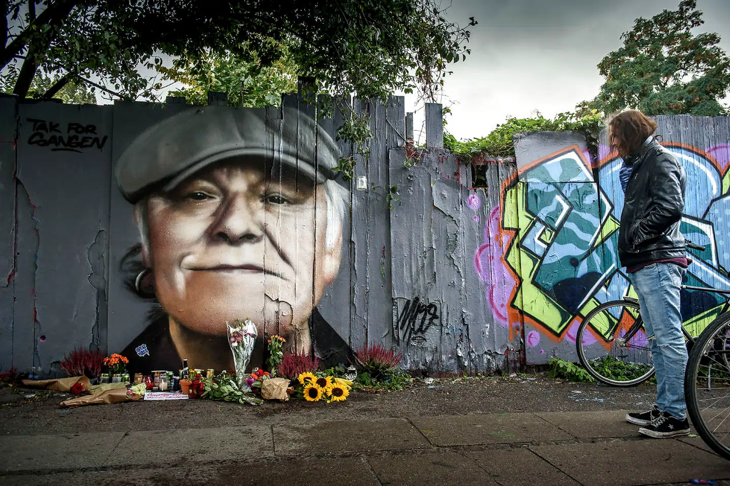 Blomster, øl, cigaretter og hilsner er lagt foran det portræt, der er blevet malet af kunstneren MPO på hegnet ind mod Christiania på Prinsessegade i København.