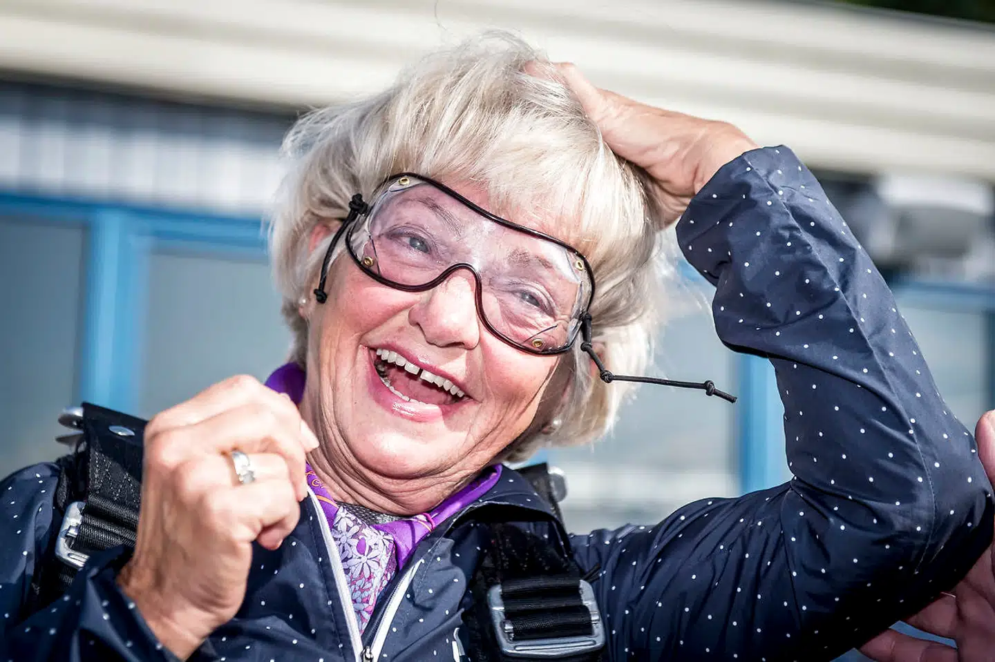 Pia Kjærsgaard prøver at holde på håret, men hun holder bestemt ikke altid på de stive former, som det ses her, hvor hun gør sig klar til at springe ud med faldskærm. Til sin 70 års fødselsdag sidste år fik Pia Kjærsgaard et faldskærmsudspring i gave af Dansk Folkeparti. Og  den 4. september 2018 blev det indløst ved et tandemspring over Haslev på Sydsjælland. (Foto: Mads Claus Rasmussen/Ritzau Scanpix)