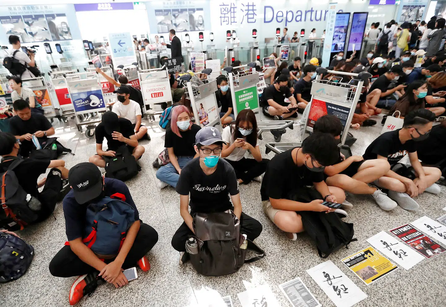 Anti-government protesters sit on the floor in front of security gates during a demonstration at Hong Kong Airport, China August 13, 2019. REUTERS/Issei Kato