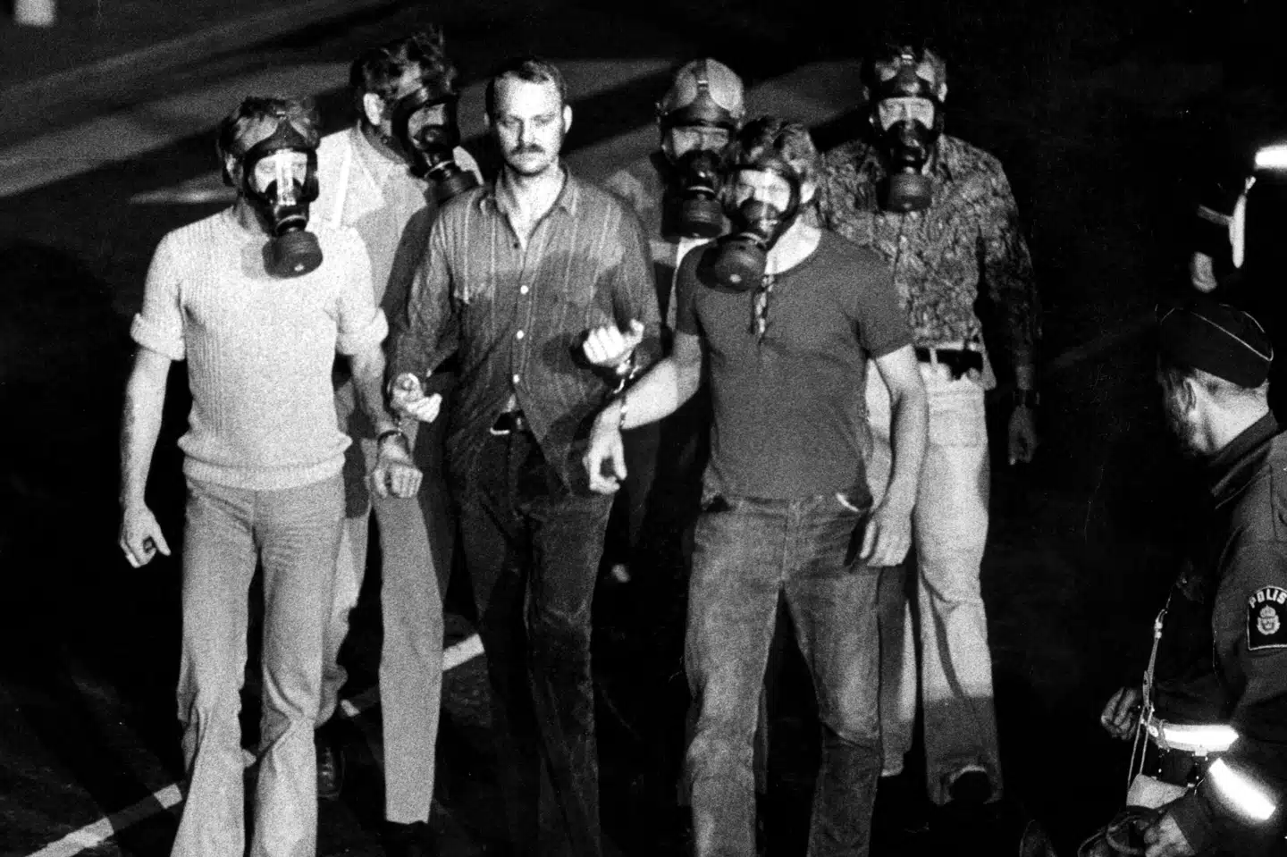 Jan-Erik Olsson bliver her - iført håndjern - ført væk af politiet, efter seks dages gidseldrama i den svenske hovedstad, Stockholm. (Arkivfoto). Egan-Polisen/Ritzau Scanpix