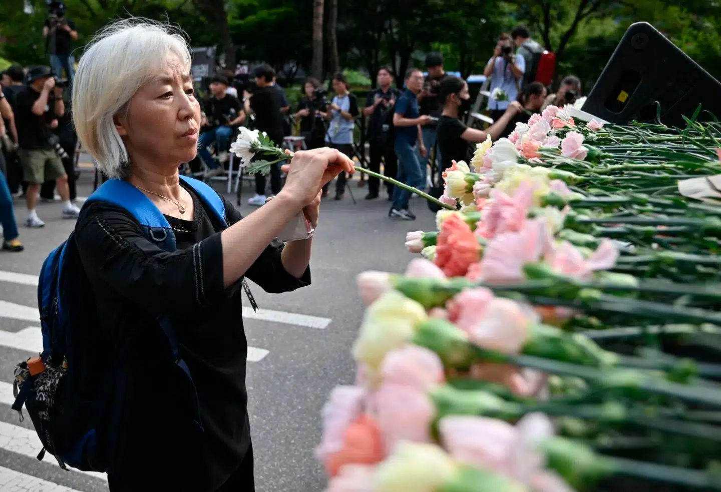 En lærer lægger en blomst ved en mindeplads for den 23-årige lærer, der tog sit eget liv. Hendes død har ført til en sjældent stor protest blandt Sydkoreas lærere. Nu advarer deres fagforenings direktør mod at gentage landets fejl.
