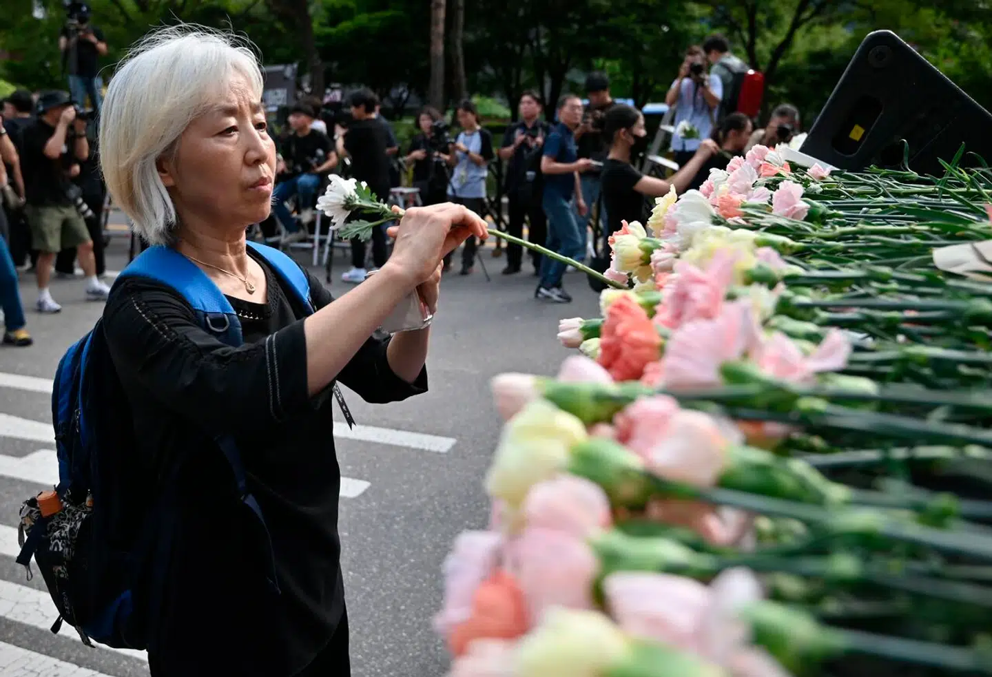 En lærer lægger en blomst ved en mindeplads for den 23-årige lærer, der tog sit eget liv. Hendes død har ført til en sjældent stor protest blandt Sydkoreas lærere. Nu advarer deres fagforenings direktør mod at gentage landets fejl.