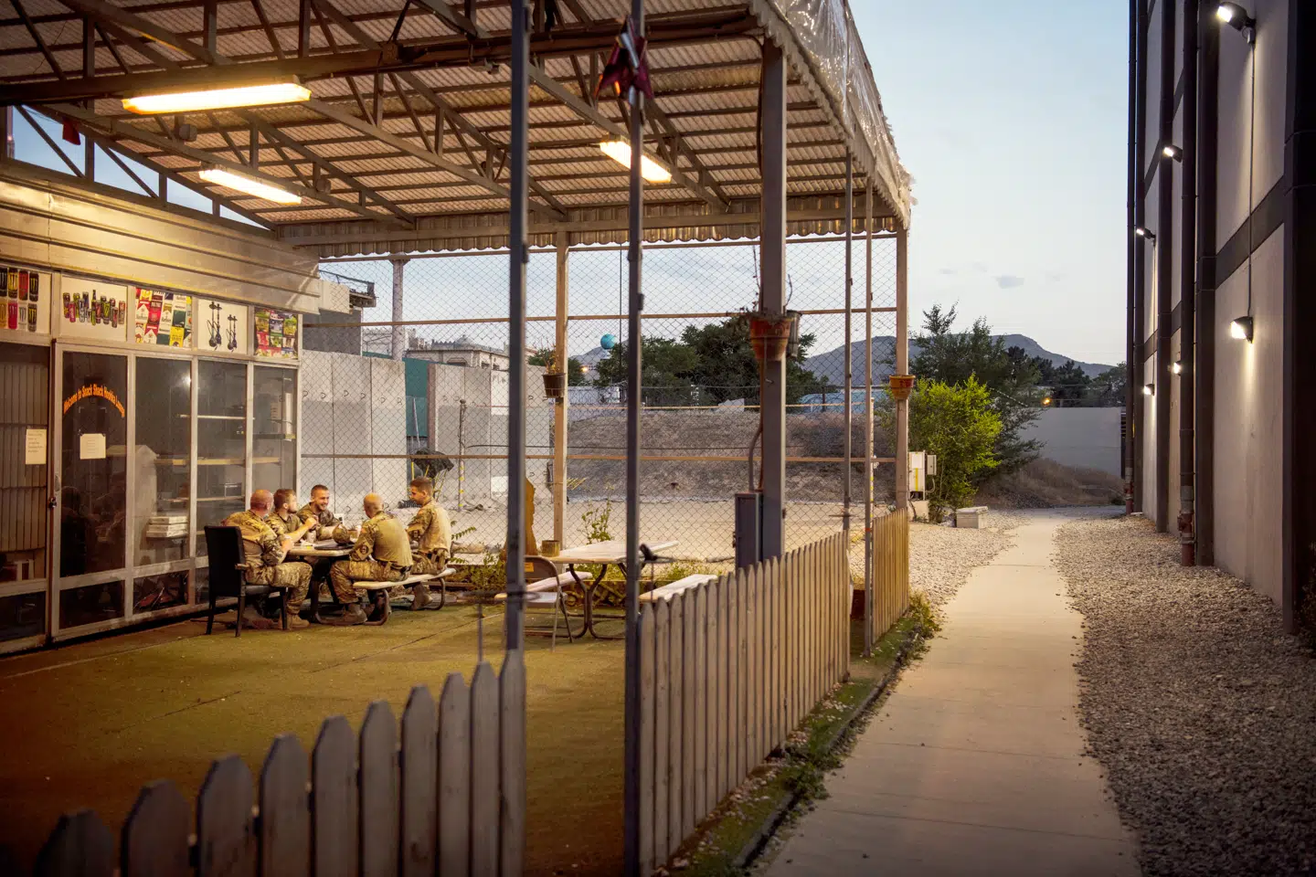 Danskere får en alkoholfri øl i den øde lejr. En times kørsel derfra fortsætter kampene mellem den afghanske regeringshær og Taleban. Foto: Andrew Quilty