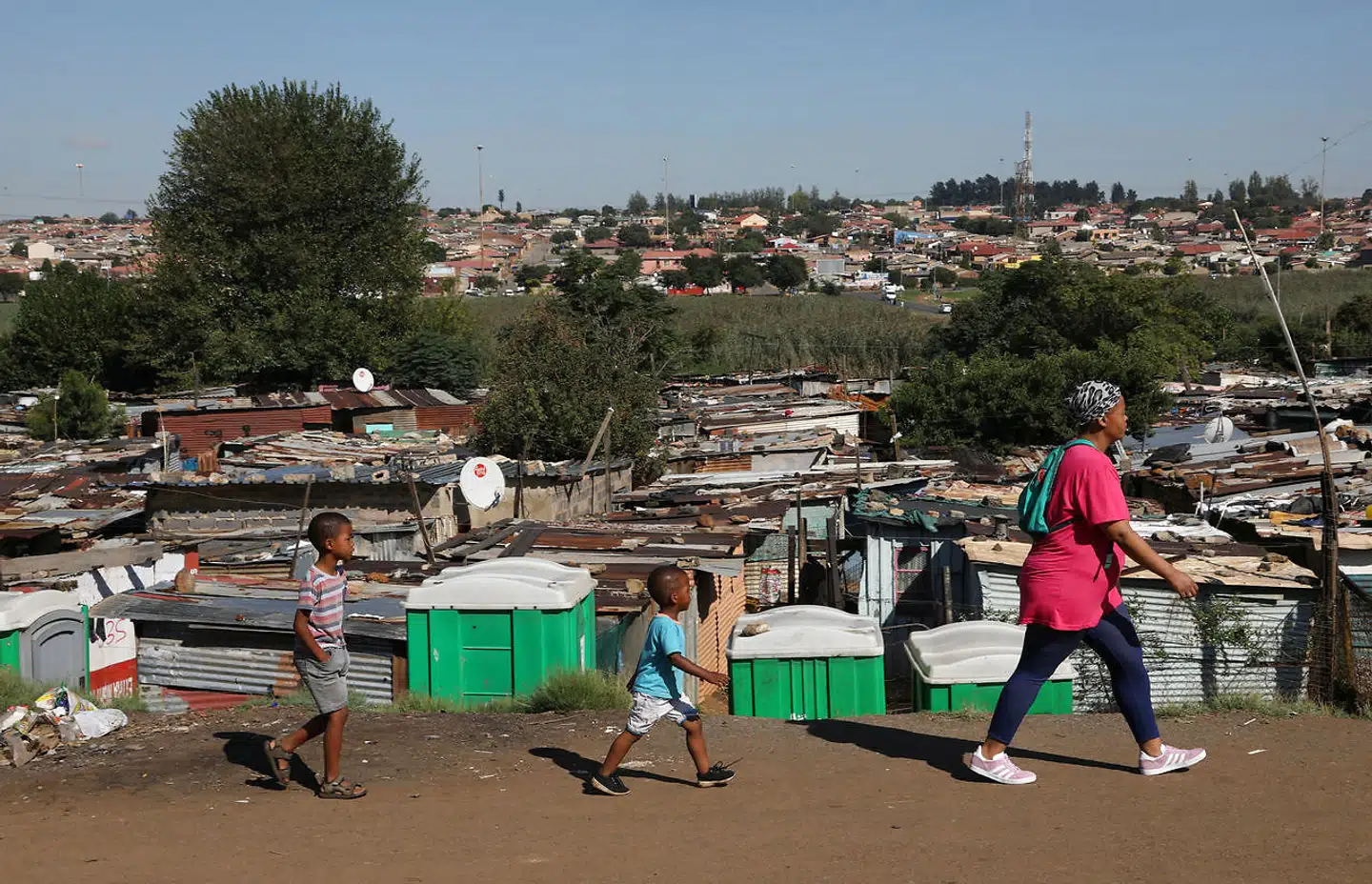 En mor og hendes børn passerer toiletterne i Kliptown i Soweto i Sydafrika. Foto: Siphiwe Sibeko / Reuters