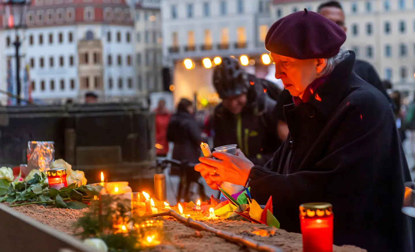 En kvinde tænder et lys for at minde ofrene for bombningen af Dresden for 75 år siden. Foto: Matthias Rietschel/ritzau Scanpix