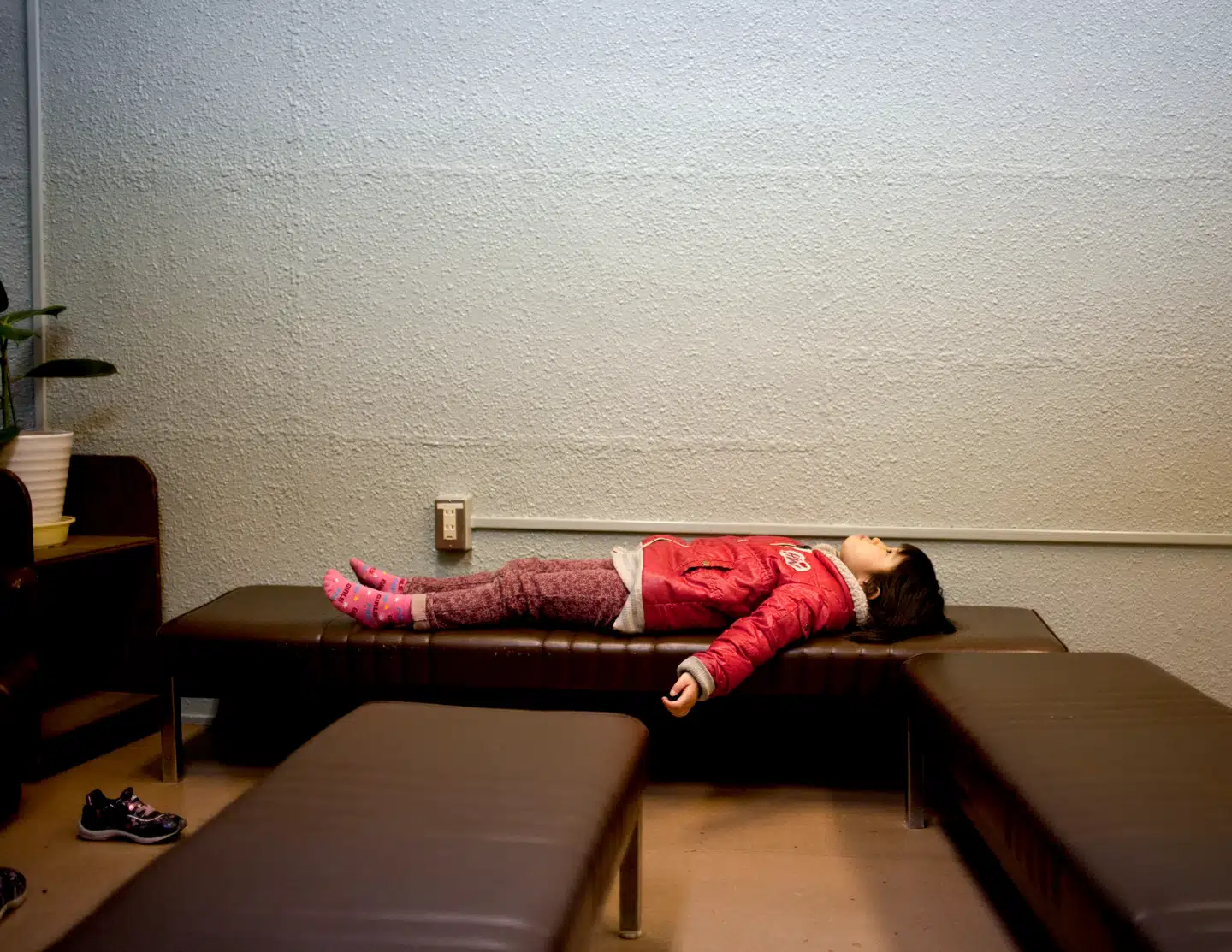 En ung pige tager et hvil, mens flere hundrede evakuerede demonstrerer for at få nogen stillet til ansvar for ulykken (2014). Foto: Redux/Scanpix