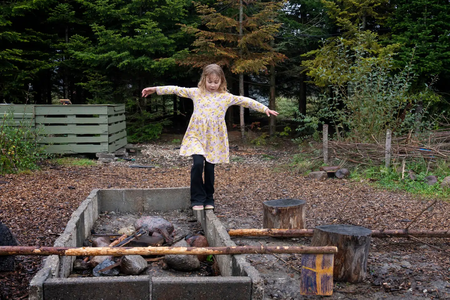 Børnene kan både lege i skoven, der ses bagved, på den store mark, hvor skolen ligger, og her på bålstedet, som en af eleverne balancerer på.