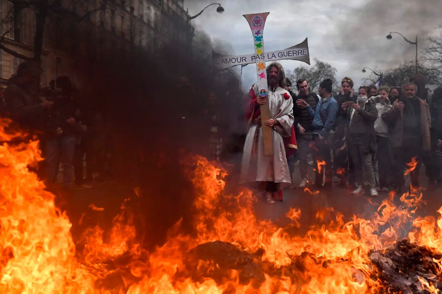 En demonstrant i Paris er klædt ud som Jesus og holder et skilt med teksten 'kærlighed ikke krig', der var dog mere krig end kærlighed på Place de la Nation tirsdag aften