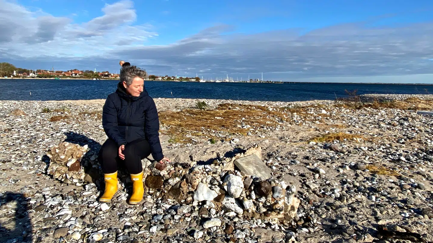 Grethe Røndal Christensen sidder på den placering på billedet, hvor hendes strandhus stod for få dage siden.