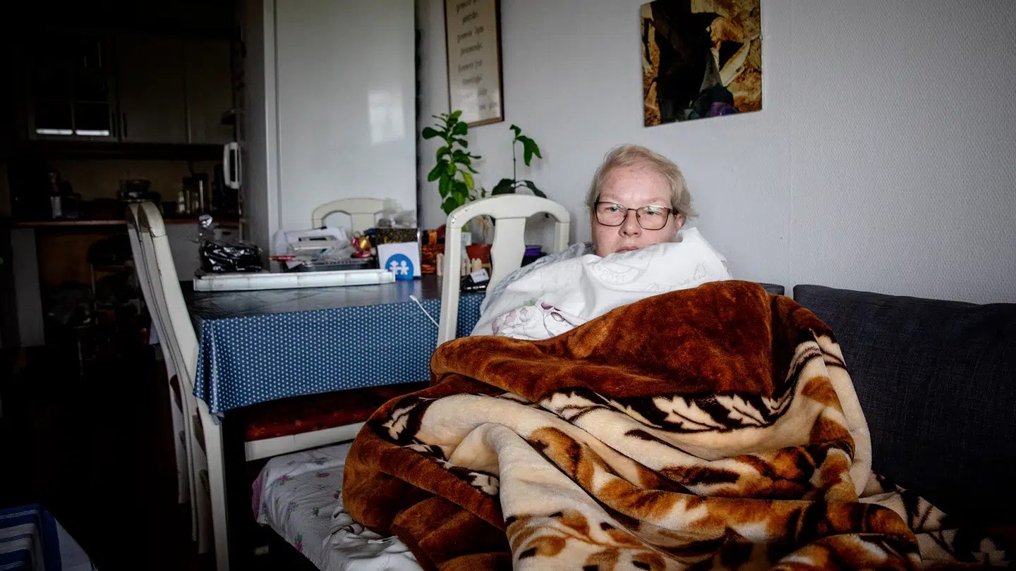 63-årige Anna Genfeldt under de tre lag tæpper og dyner i sin stue.