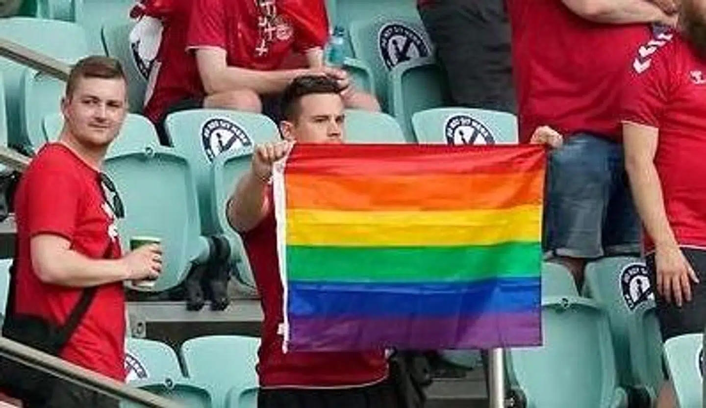 En dansk fan holder et regnbueflag op på stadion i Baku.