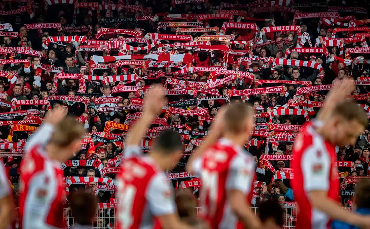 (FILES) In this file photo taken on March 08, 2019 FC Union Berlin players wave as supporters display their scarves prior to the 2nd division Bundesliga match FC Union Berlin vs FC Ingolstadt 04 at the stadium An der Alten Foersterei in Berlin. - Three decades after the fall of the Berlin Wall, the German capital's FC Union and Hertha Berlin will meet for their first Bundesliga derby, with fans wondering if a real rivalry will grow or if the spirit of reunification will prevail. (Photo by John MACDOUGALL / AFP)