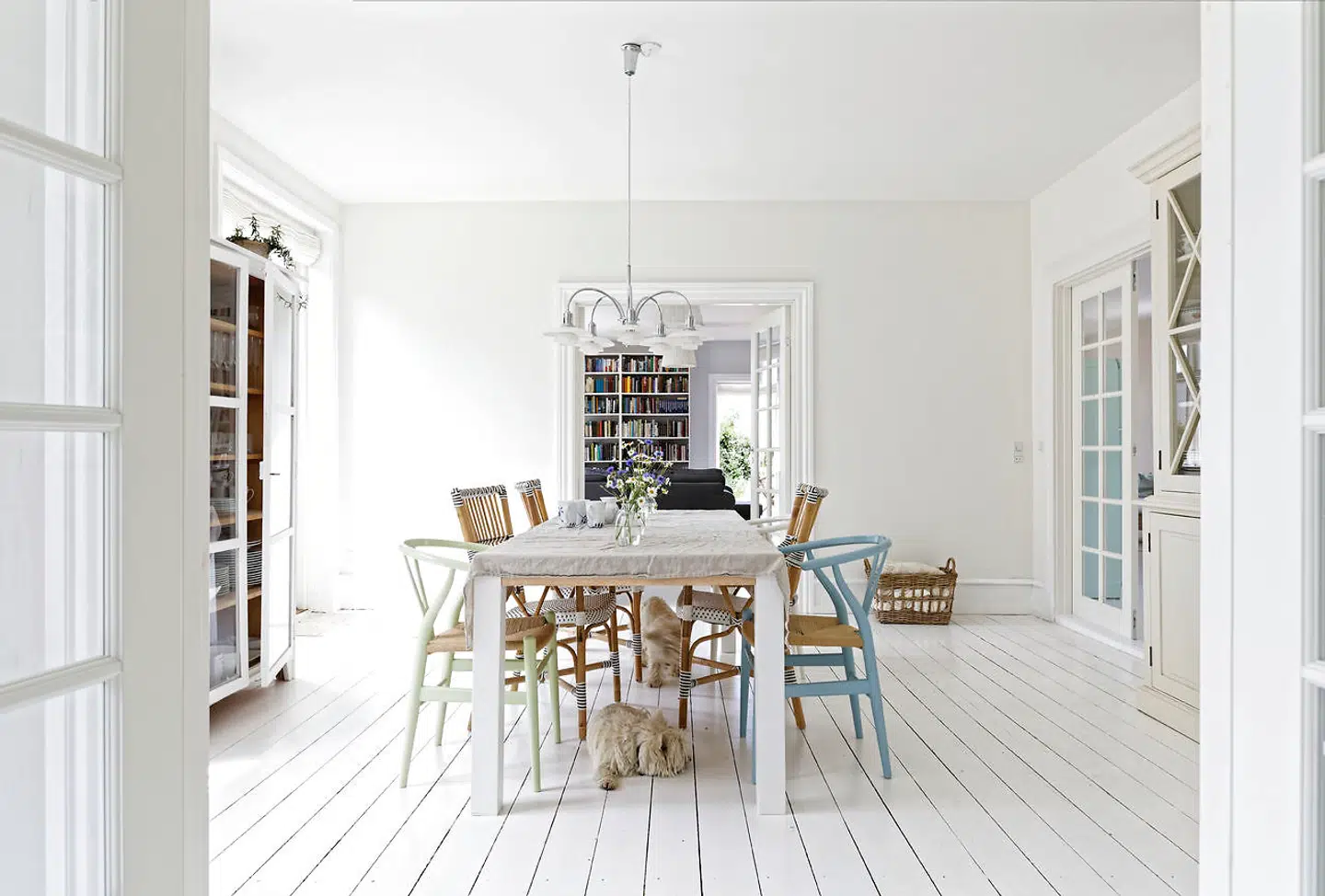 Spisestuen mellem de to stuer har PH-lysekrone og blandede stole – herunder to tre pastelfarvede Hans J. Wegner Y-stole.