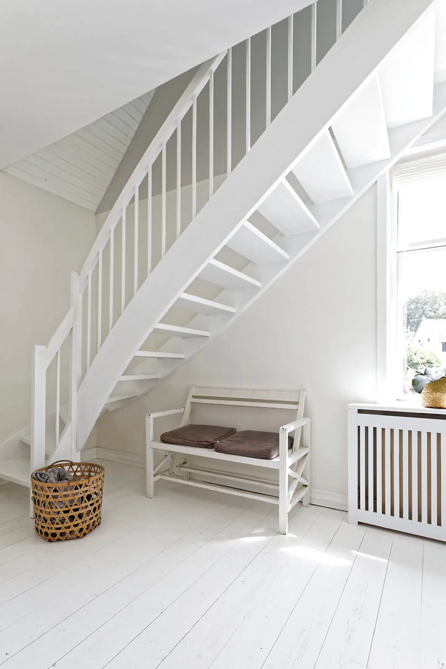 I hallen, hvor alt er malet hvidt, har en ny trappe afløst en ældre, der ikke matchede parrets stil. En radiatorskjuler er også kommet til.