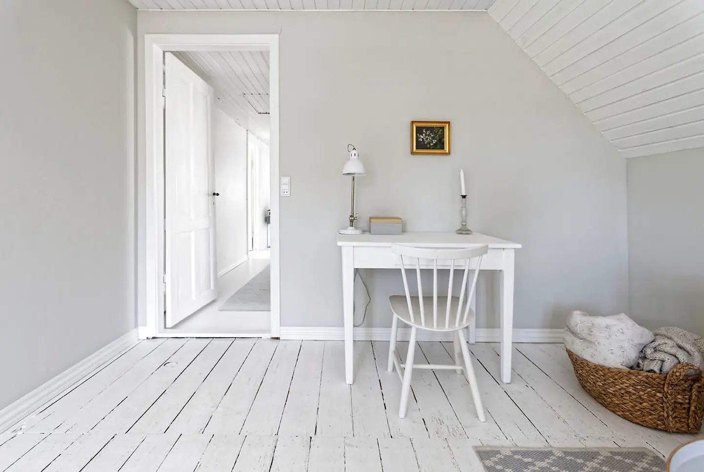 Den hvidmalede repos er enkelt møbleret med en lille skriveplads.