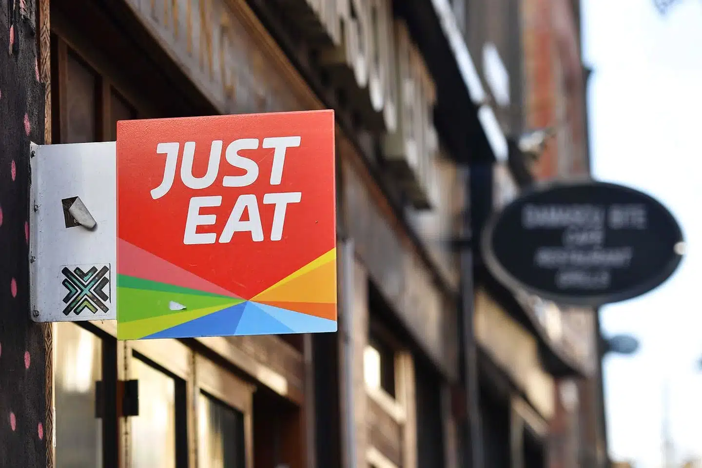 A sign for Just Eat, a food delivery service can be seen above a restaurant in London on December 18, 2017. Just Eat has been welcomed on December 18, 2017 into UK's FTSE 100 index of the country's largest publicly listed companies. / AFP PHOTO / BEN STANSALL