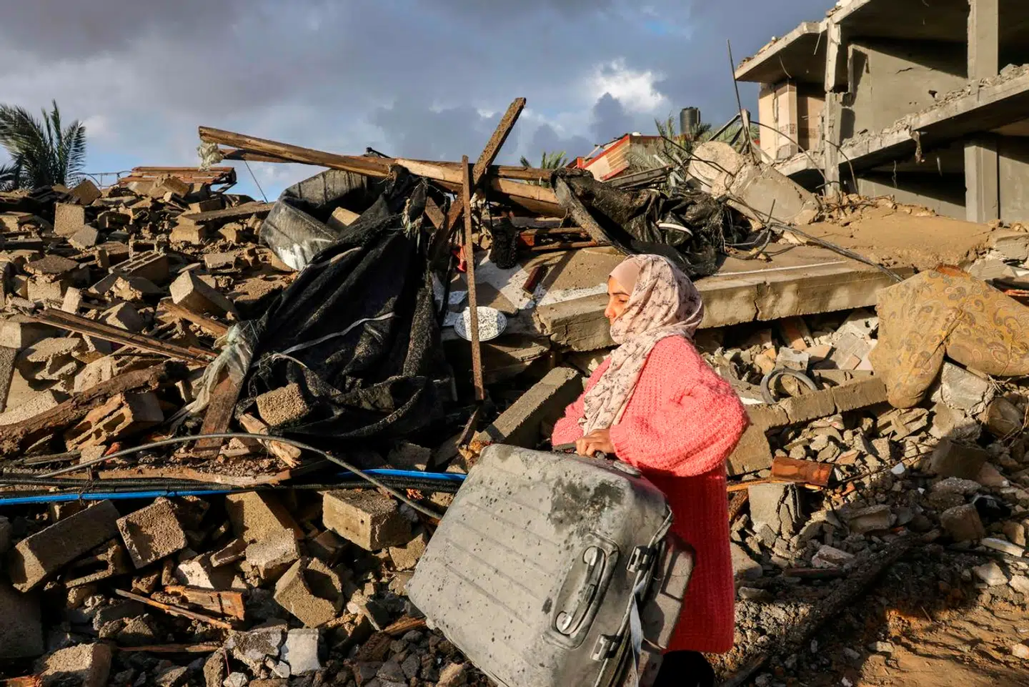 En palæstinensisk kvinde leder efter sine ejendele ved en bygning, der er kollapset under israelske bombardementer i det sydlige Gaza.