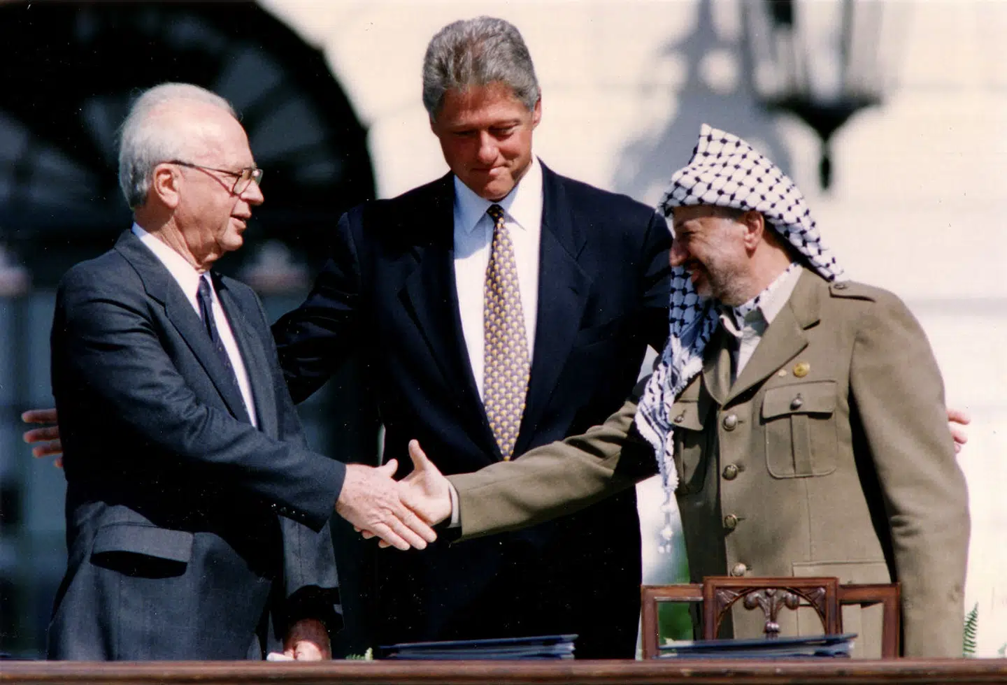 PLOs leder Yasser Arafat giver hånd til Israels daværende premierminister Yitzhak Rabin i Washington, D.C., mens USAs præsident Bill Clinton ser på. Det var et led i Oslo-fredsprocesserne i 1993. De førte ikke til noget. Og der er desværre nu lang vej tilbage til noget lignende.
