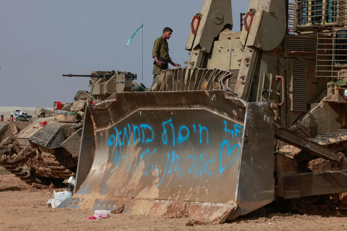 Israelske soldater og militærkøretøjer holder søndag klar ved grænsen til Gazastriben til at rykke ind og støtte den igangværende offensiv. Med blå skrift på bulldozerens grab står: "Vores mission er at ødelægge Hamas".