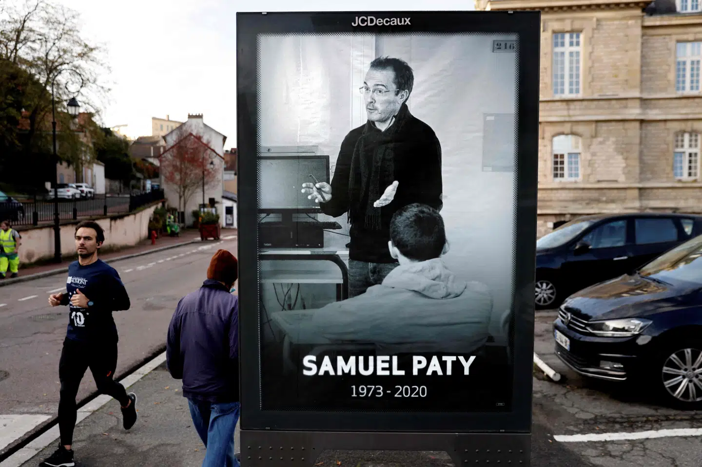 Fodgængere passerer et billede af den dræbte lærer Samuel Paty i byen Conflans-Sainte-Honorine, der ligger omkring 30 kilometer nordvest for Paris. Fredag er seks teenagere blevet dømt i forbindelse med drabet på ham. (Arkivfoto)