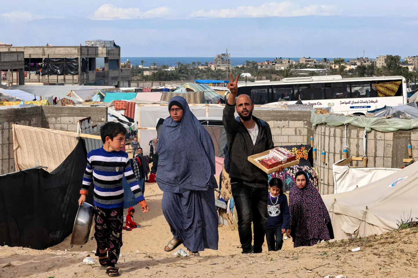 En gruppe palæstinensere, som er blevet fordrevet af den intense israelske militæroffensiv i Gazastriben, går lørdag i et område nær Rafah-grænsen mod Egypten, hvor mange familier har slået telte op som midlertidige boliger.