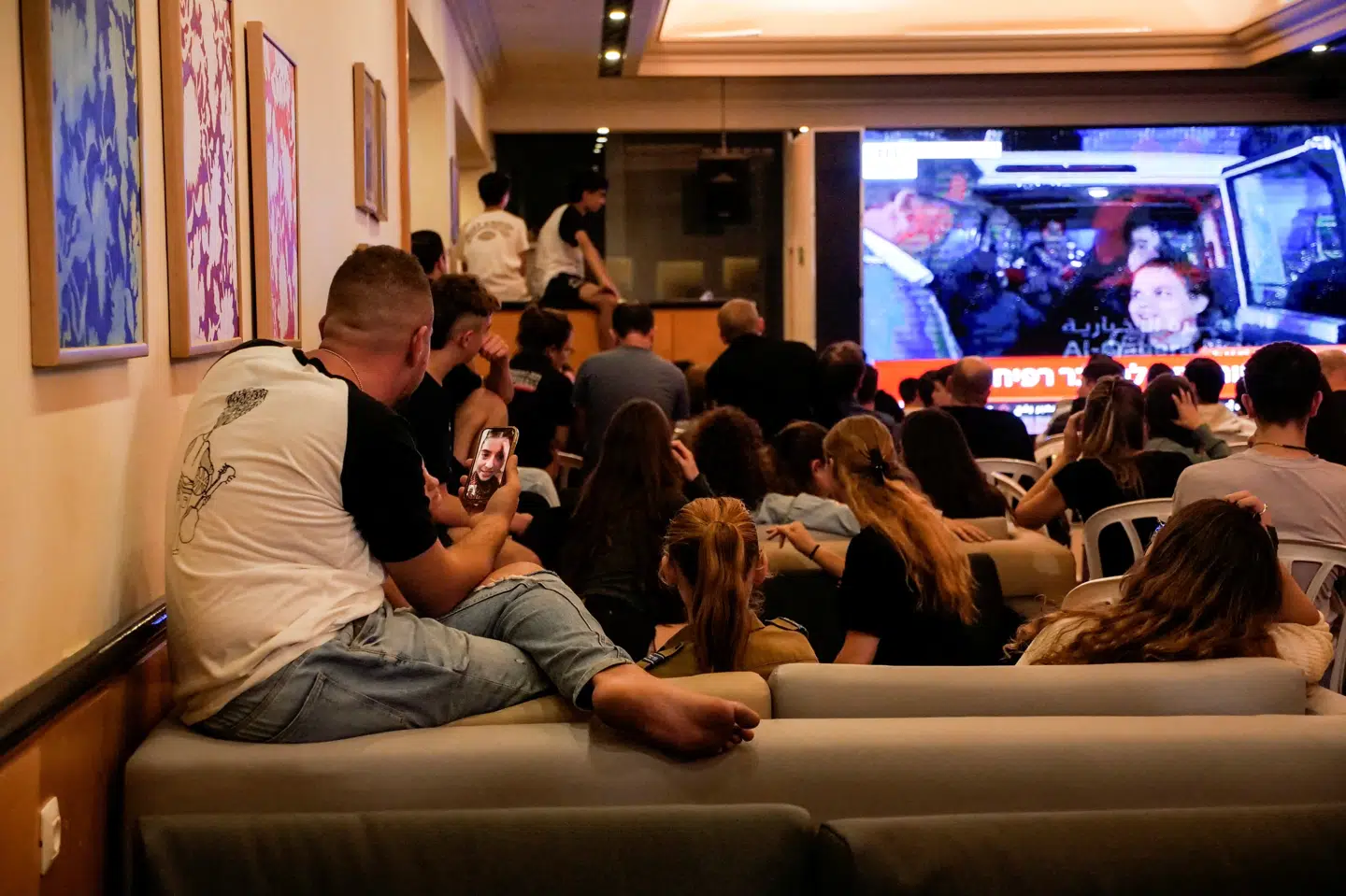 På et hotel, som de er evakueret til, følger beboere fra den israelske kibbutz Beeri med i nyhederne under en af de udvekslinger af fanger og gidsler, som Hamas og Israel gennemførte i slutningen af november. Nu melder både kibbutzen og Hamas et af gidslerne fra Beeri dræbt. (Arkivfoto)