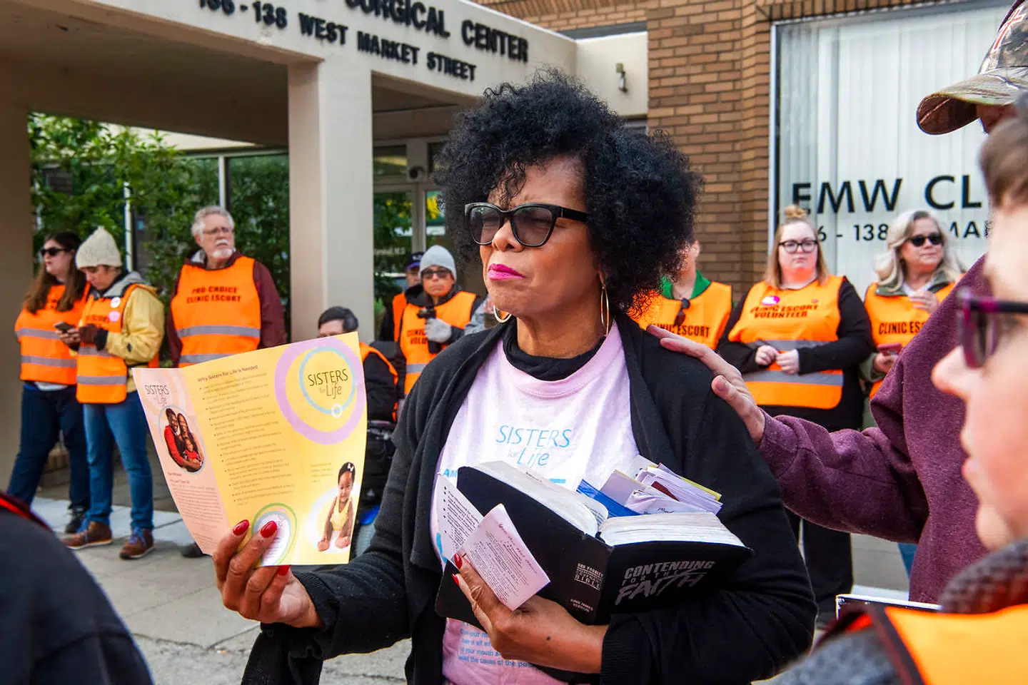 Beverly Johnson er aktivist fra organisationen Sisters for Life, som også bekæmper fri abort. Denne dag fortæller Beverly Johnson glad, at hun »i dag har reddet et liv«, fordi hun har overbevist en 29-årig sort kvinde om alligevel ikke at få abort. Den 29-årige kvinde har dog fortsat tænkt sig at få en abort. I baggrunden – iført orange veste – klinikledsagere, der forsøger at hjælpe kvinderne uhindret hen til abortklinikken.