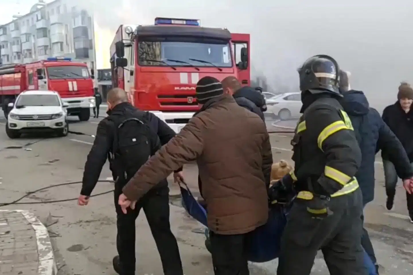 En brandmand og flere indbyggere evakuerer en såret person fra det område i byen Belgorod, der ifølge russiske myndigheder er ramt af et ukrainsk angreb lørdag.