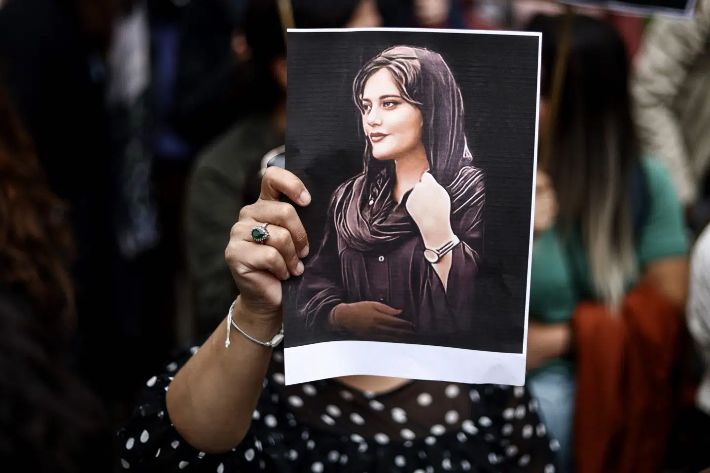 Demonstrant i Iran viser foto af Mahsa Amini, som blev anholdt og døde i politiets varetægt, efter at en lok af hendes hår havde været synlig på gaden.